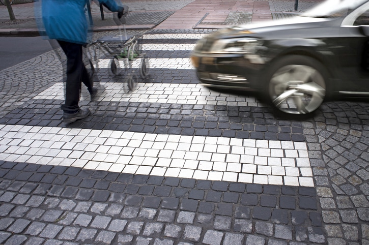 Senior citizen crossing street with fast car approachingSenior citizen crossing street with fast car approaching