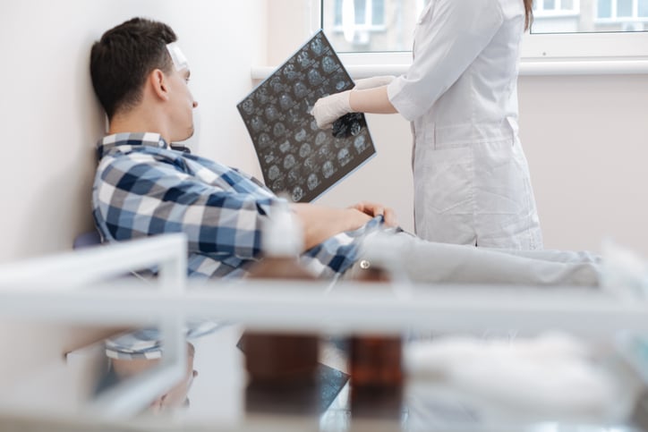 Here is the problem. Nice professional female doctor holding an X ray photo and pointing at it while explaining the patient his problem